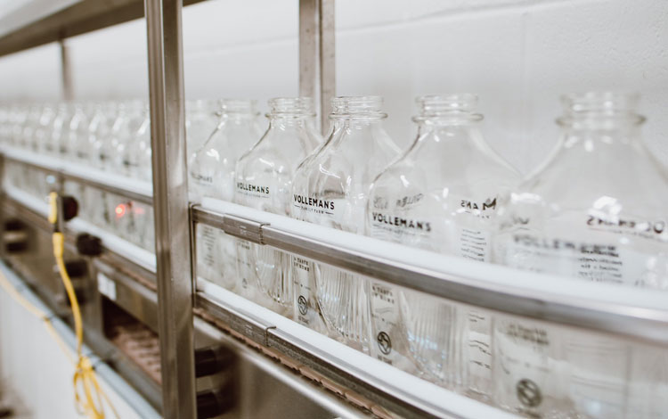 Botellas de vidrio en la línea de embotellado a punto de llenarse de leche